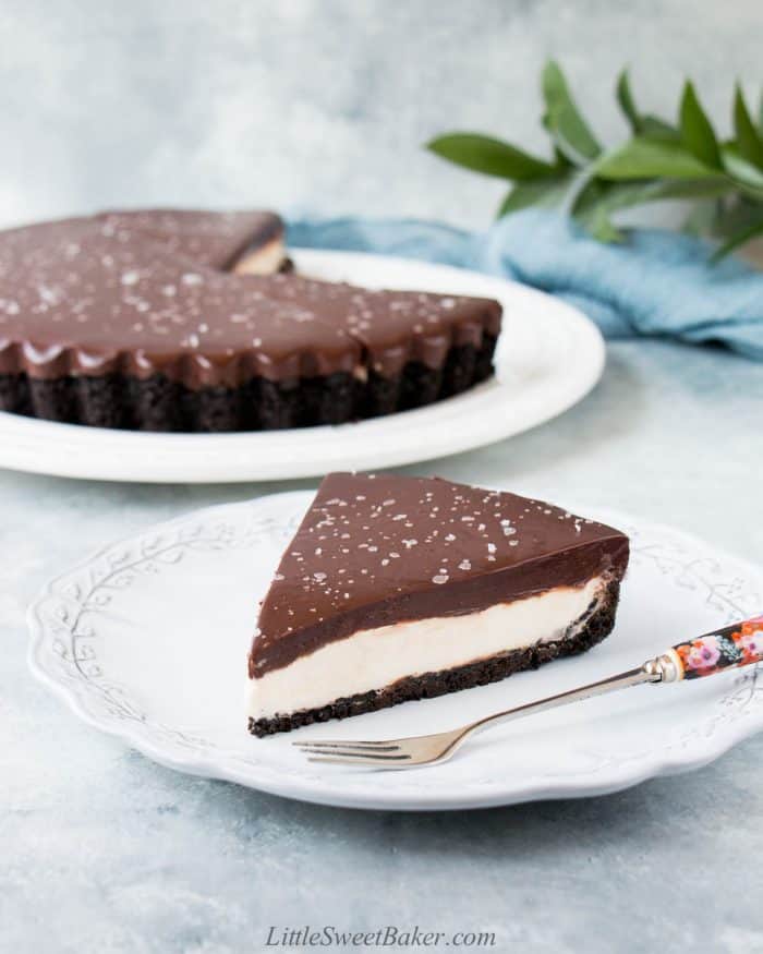A slice of salted dark chocolate mascarpone tart on a light grey plate with a floral fork.