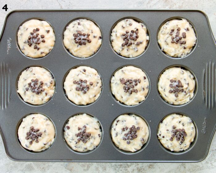 A muffin pan filled with chocolate chip muffin batter.