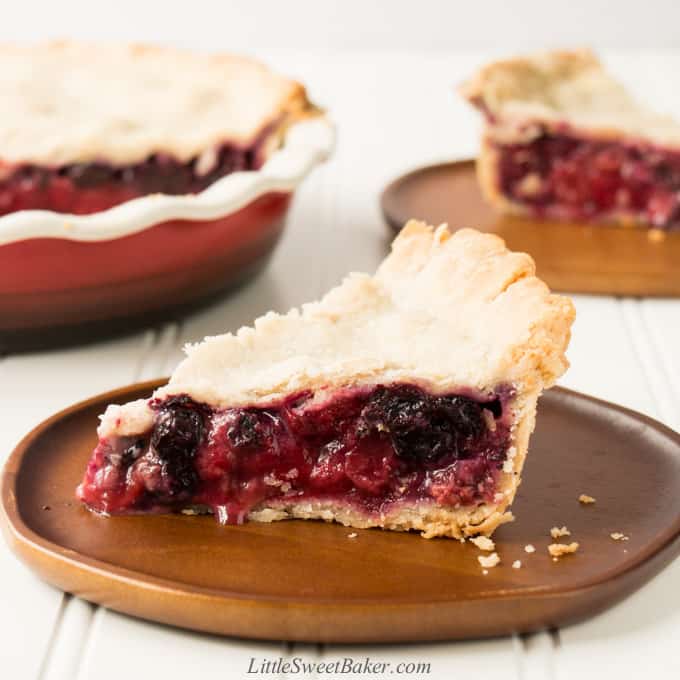 A slice of mixed berry pie on a wooden plate.