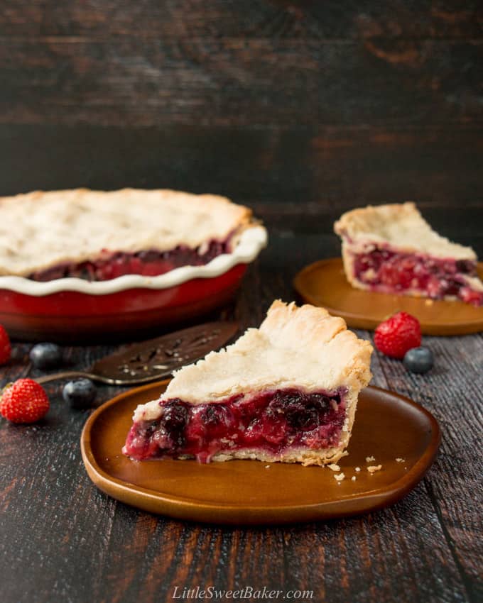 A slice of mixed berry pie on a wooden plate.