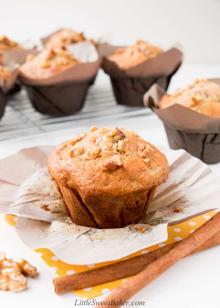 A banana nut muffin on a yellow polka-dot napkin with two cinnamon sticks.