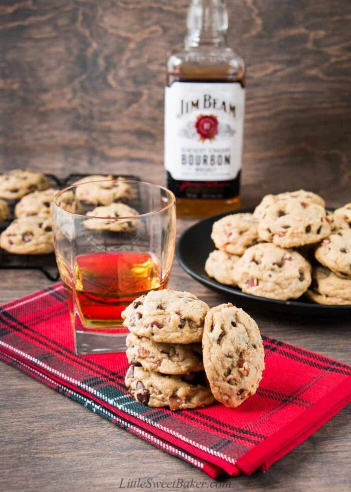 Bourbon bacon chocolate chip cookies on a red napkin with a glass of bourbon.