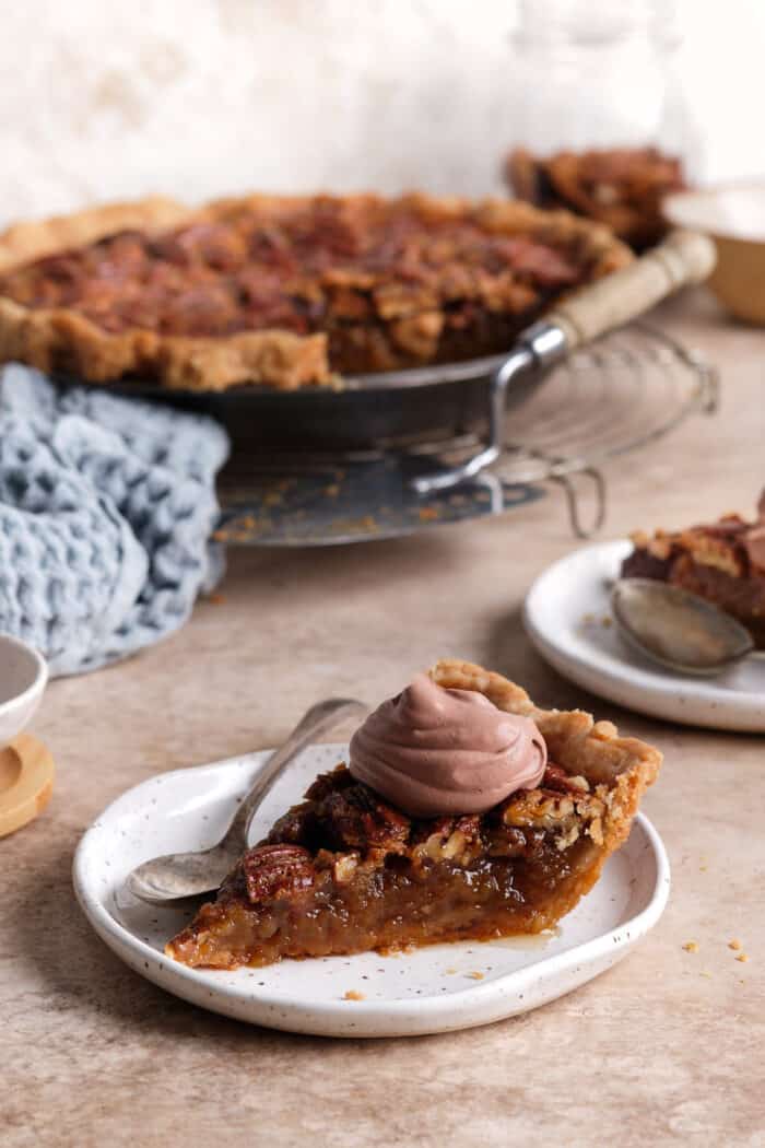 A slice of pecan pie topped with chocolate whipped cream