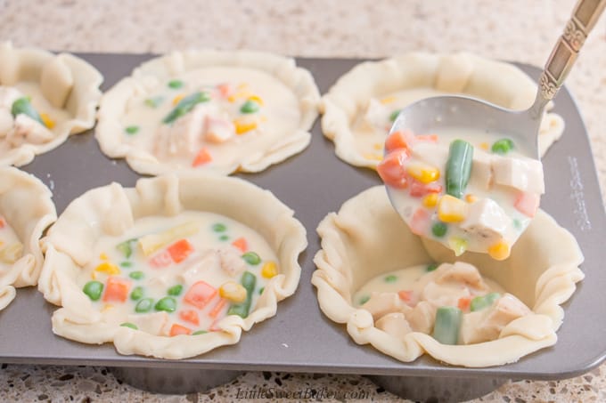A ladle pouring turkey pot pie fillings in pie crust.
