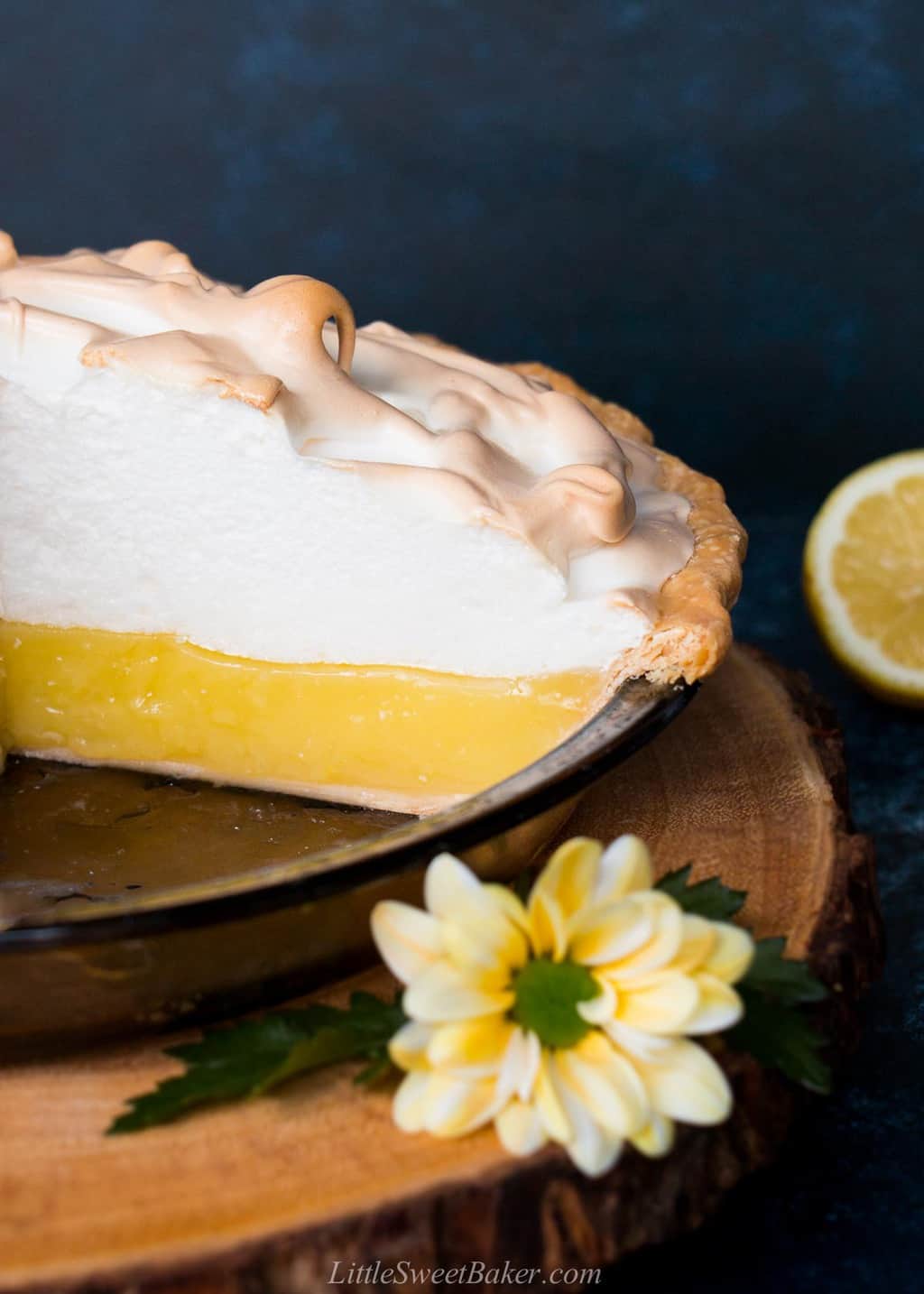 A cross section of a homemade lemon meringue pie on a wooden board.