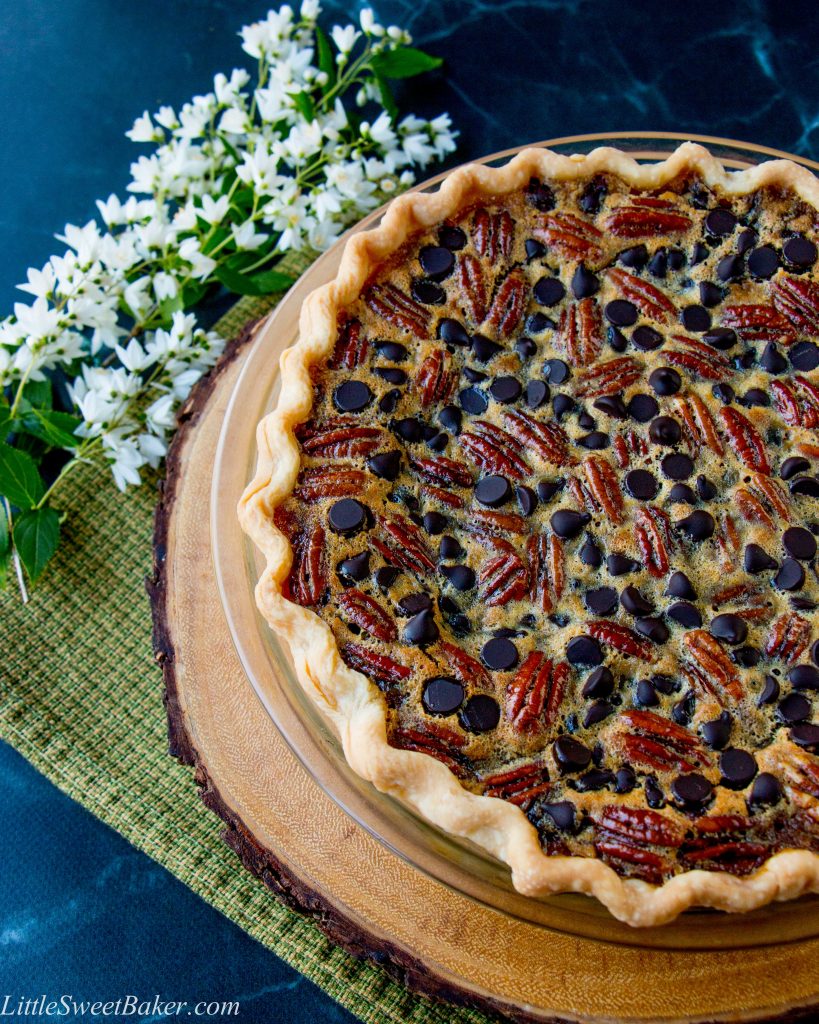 a chocolate pecan pie on a wooden board and green dish towel