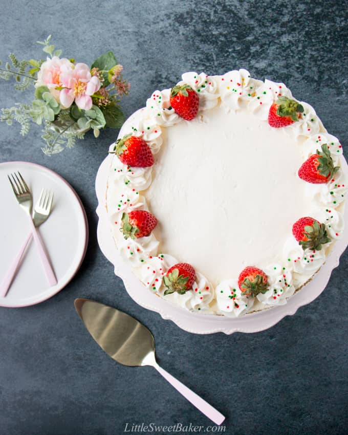 A top view of a no-bake cheesecake topped with whipped cream, strawberries and sprinkles.