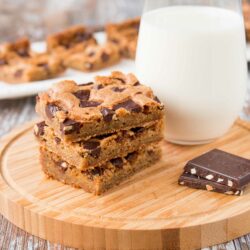 These chewy chocolate chunk cookie bars are so much easier to make than cookies. One bowl, one pan and done! #chocolatechipcookiebars #cookiebars #christmascookies #chocolatechunkcookies #chocolatechunkcookiebars