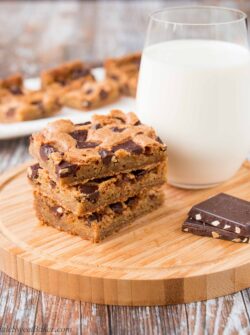 These chewy chocolate chunk cookie bars are so much easier to make than cookies. One bowl, one pan and done! #chocolatechipcookiebars #cookiebars #christmascookies #chocolatechunkcookies #chocolatechunkcookiebars