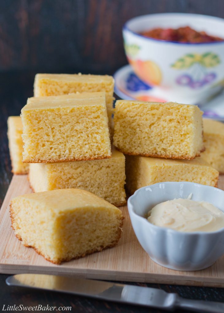 Southern-style cornbread stacked on a cutting board with a bowl of chili in the background.