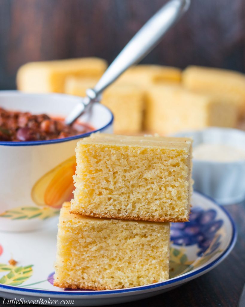 Two pieces of buttermilk cornbread on a plate with a bowl of chili