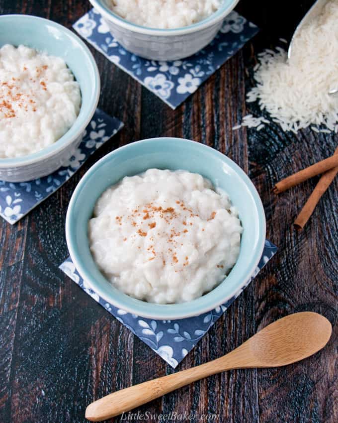 A bowl of rice pudding on a blue napkin with a wooden spoon.