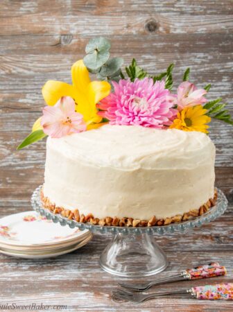 Coated in a delicious cream cheese frosting, this supremely moist banana cake has sweet pieces of pineapples and crunchy pecans mixed in. It's spiced with cinnamon and nutmeg, and sweetened with brown sugar. #hummingbirdcake #layercake #creamcheesefrosting #bananacake