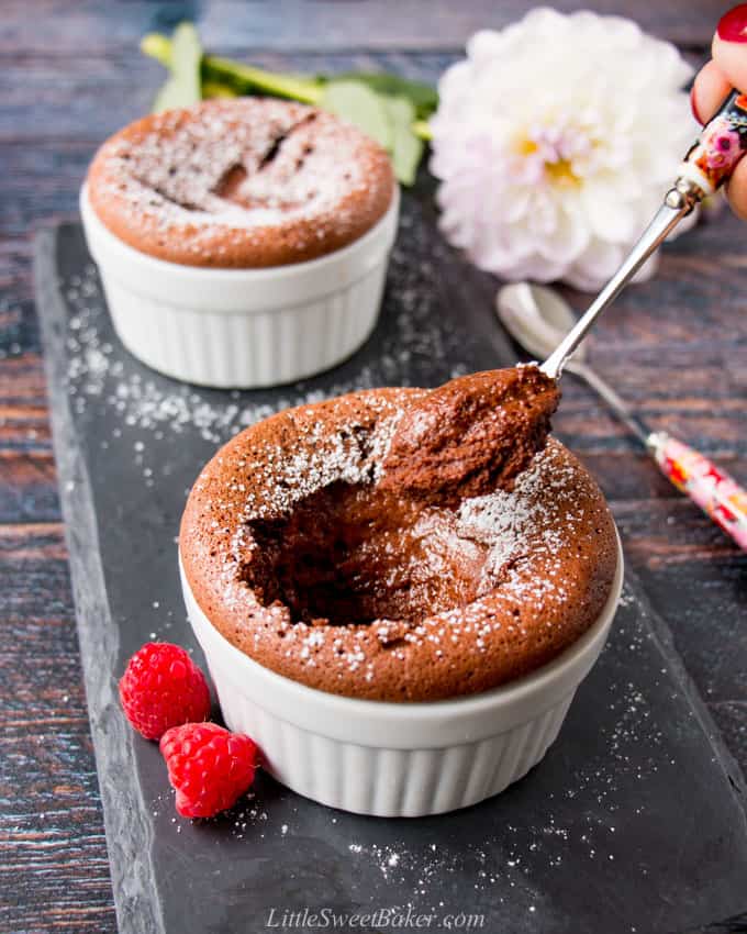 two chocolate souffles, one with a spoonful taken out of it.