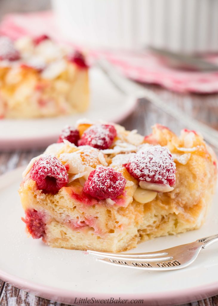 An upclose view of a slice of croissant bread pudding with fresh raspberries and almonds.