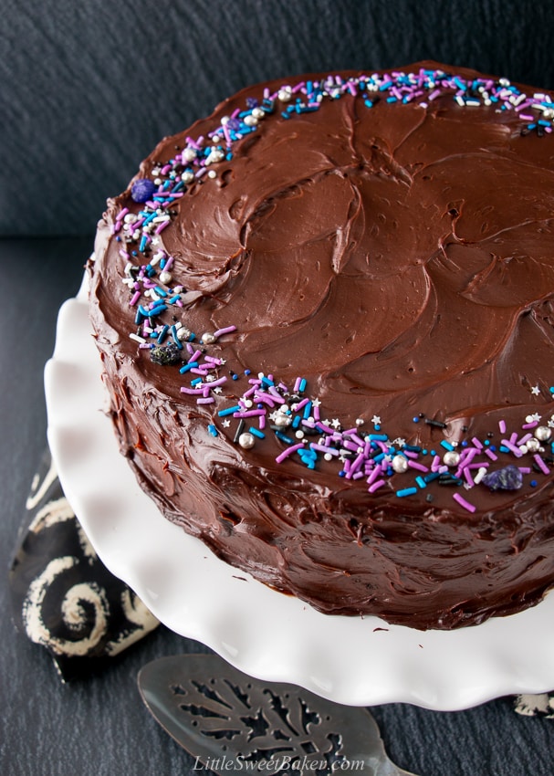 This supremely moist and tender chocolate cake is surrounded by a rich chocolate fudge frosting. It's the best chocolate cake you'll ever taste and uber easy to make! #chocolatecake #chocolatefudgecake #chocolatelayercake