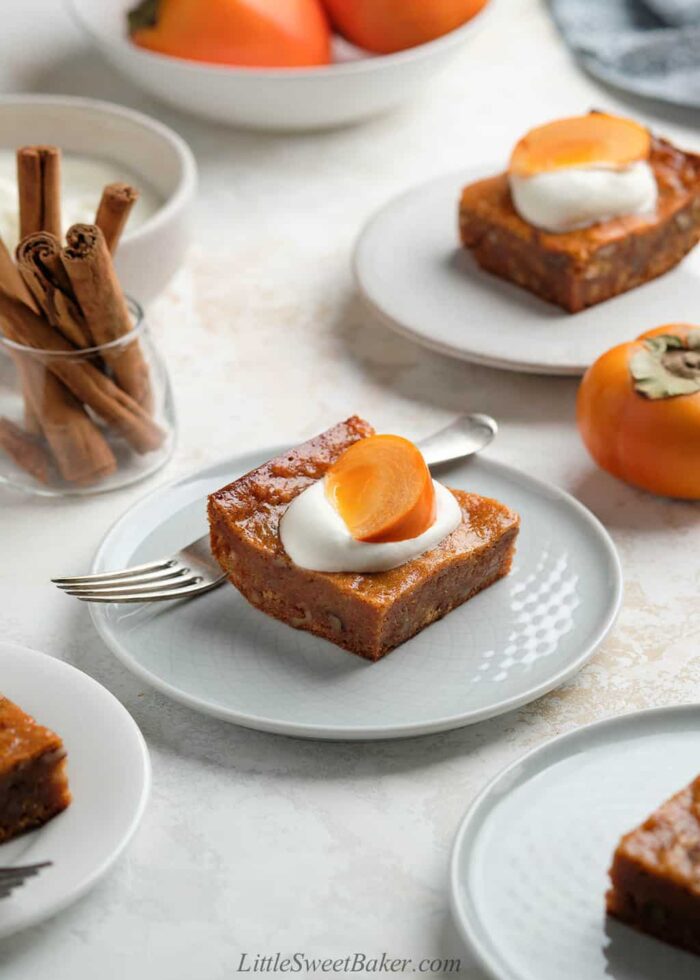 Persimmon pudding cakes topped with whipped cream and sliced persimmon fruit.