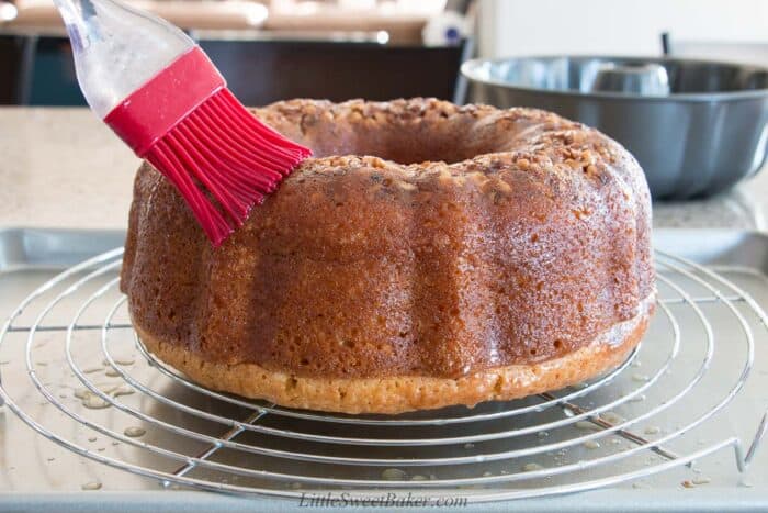 Brushing butter-rum sauce on a Bacardi rum cake on a cooling rack.