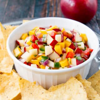 apple mango salsa in a white bowl surrounded by tortilla chips