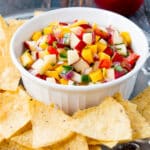 apple mango salsa in a white bowl surrounded by tortilla chips