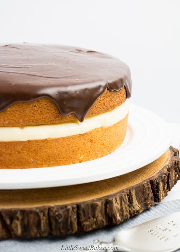 A close-up of a Boston cream pie on a white plate and wooden board.