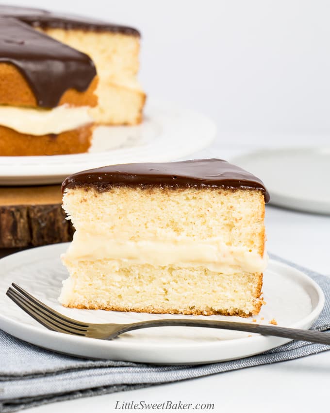 A slice of Boston cream pie on a light grey plate with fork.