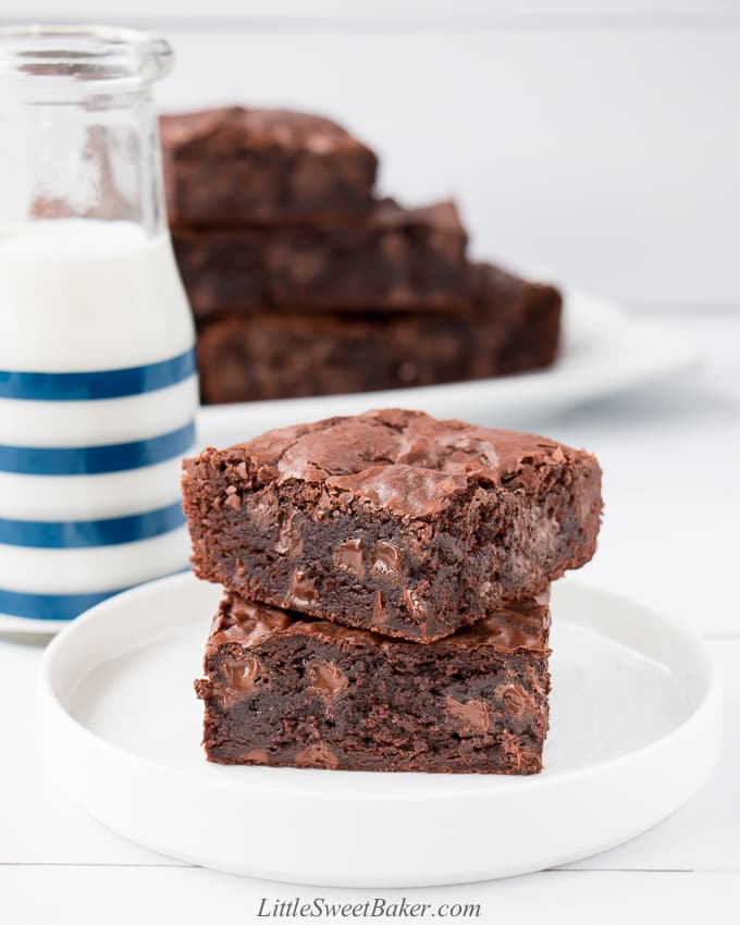 Thick dark brownies loaded with melty chocolate chips on a white plate.
