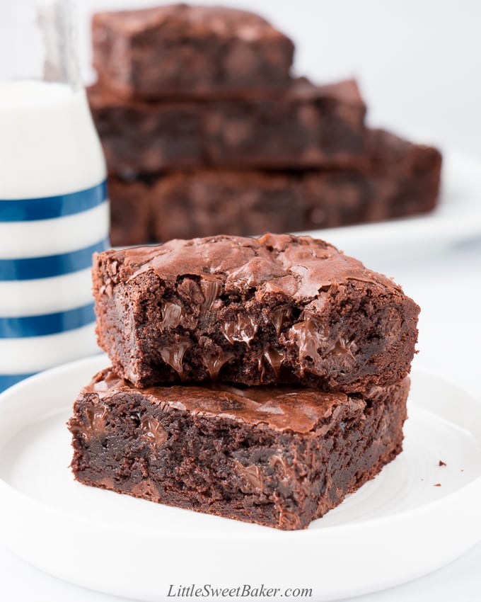 A stack of two brownies on a white plate with a bite taken out of the top one.