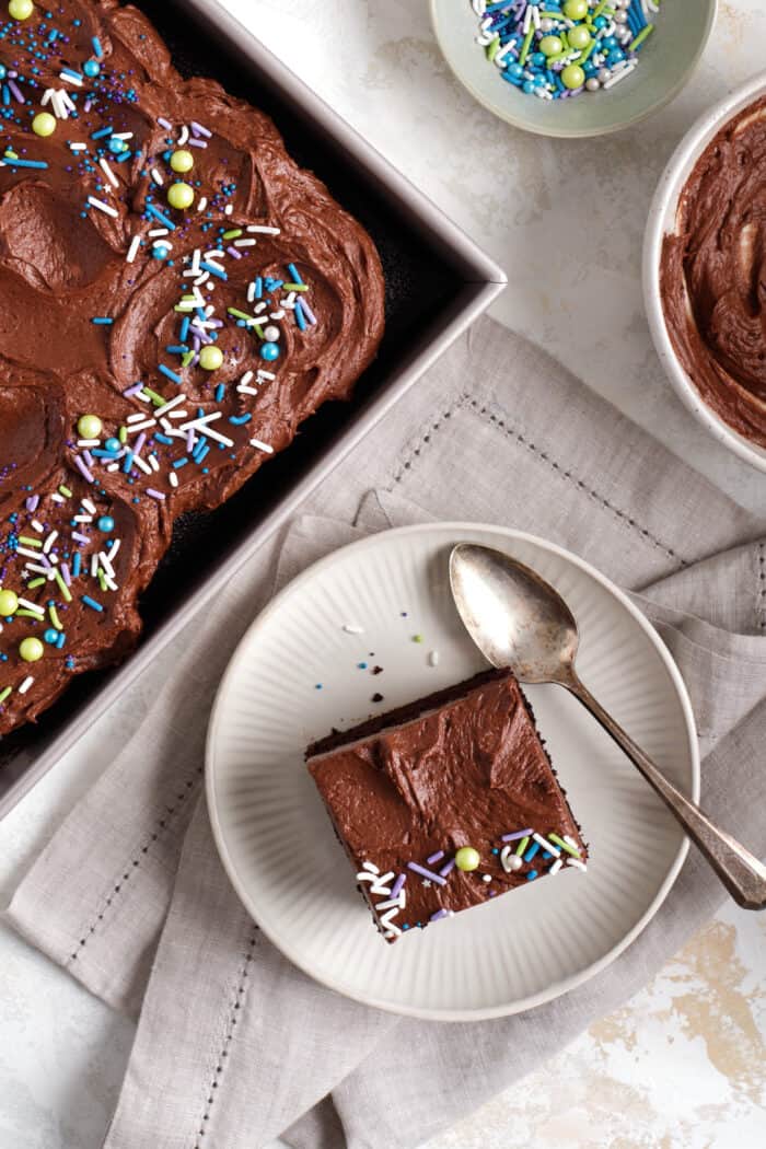 Chocolate sheet cake with sprinkles and a slice on a plate