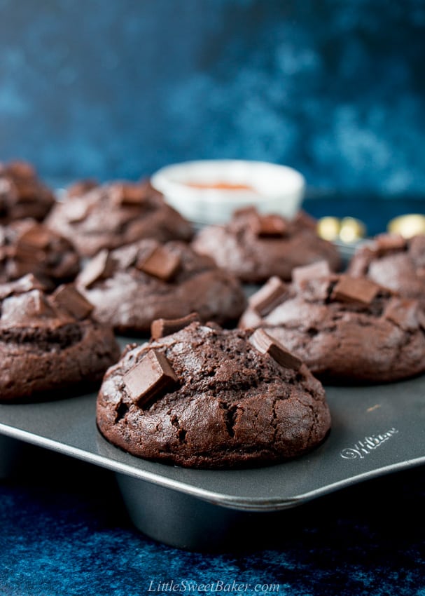 Close-up of a double chocolate muffin in a pan with a dark blue background.