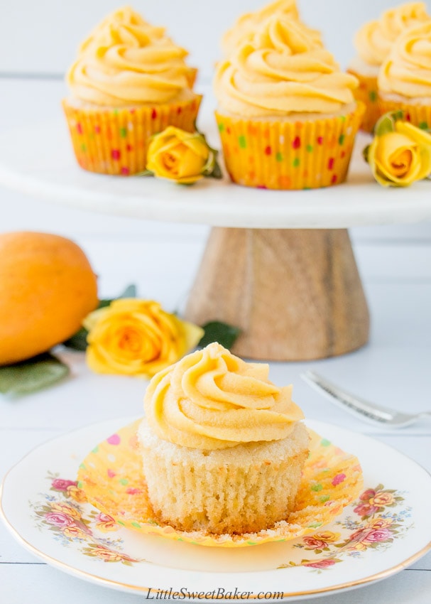 A mango cupcake on a white plate with the paper liner peeled back.