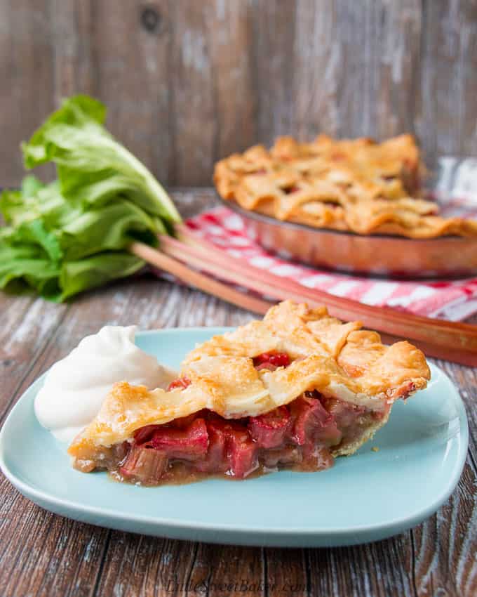 A slice of rhubarb pie with whipped cream on a light blue plate. 