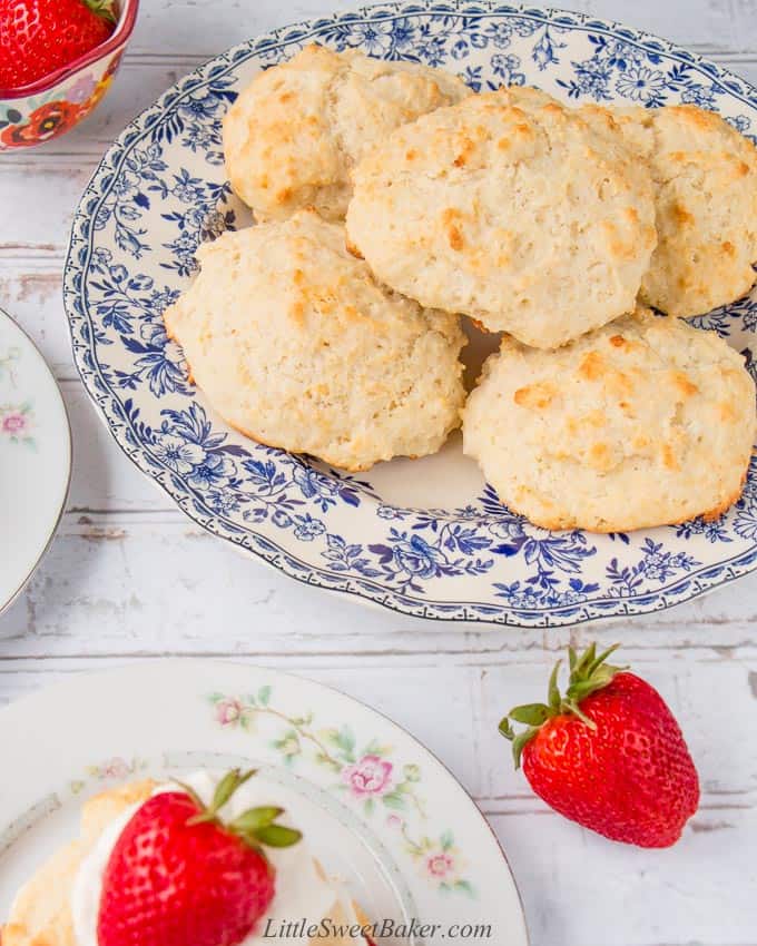 Shortcake biscuits on a blue flowered pate with a strawberry on the side.