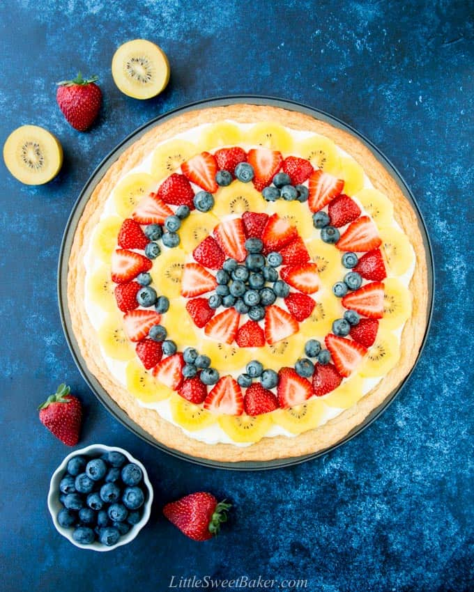 A whole fruit pizza on a blue background.
