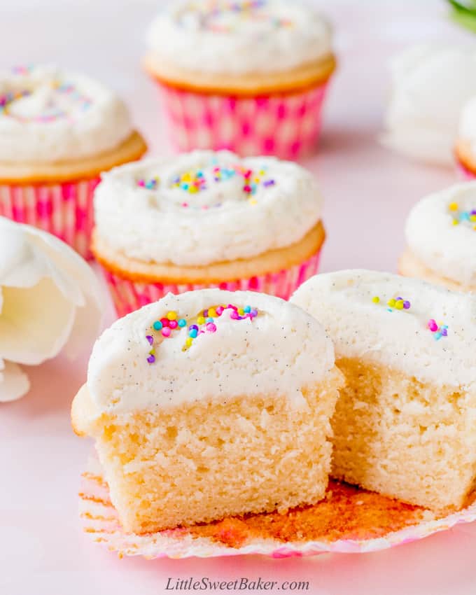 A moist vanilla cupcake topped with vanilla buttercream cut in half.