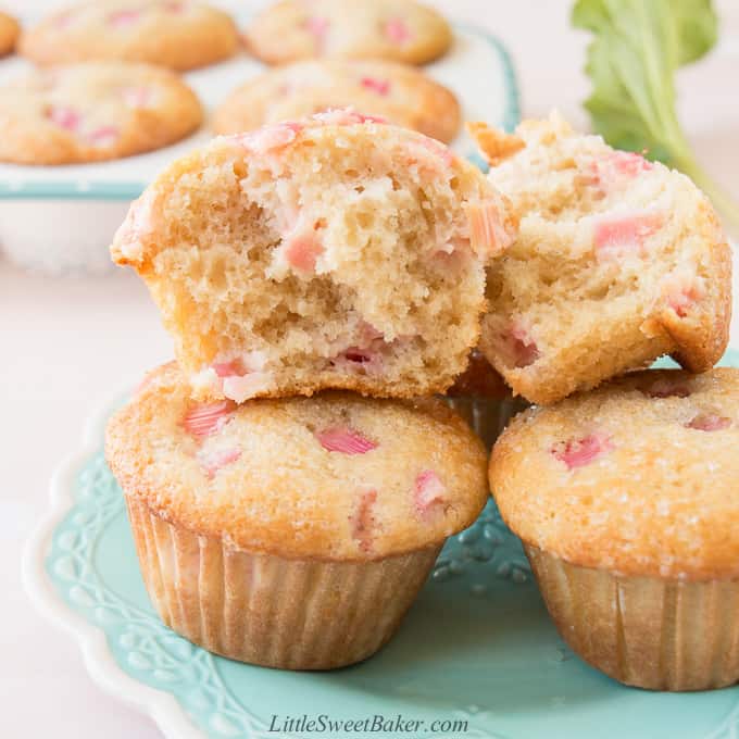 A rhubarb muffin broken in half on a stack of muffins on a teal plate.