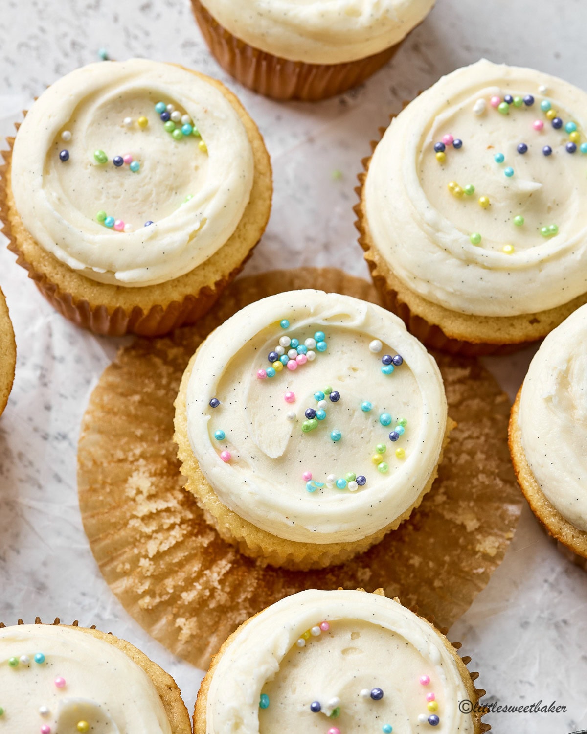 Overhead view of vanilla cupcakes topped with vanilla buttercream and sprinkles.