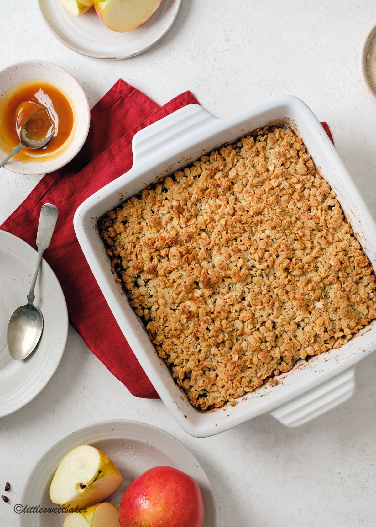 Apple crisp in a white square casserole dish on top of a red napkin