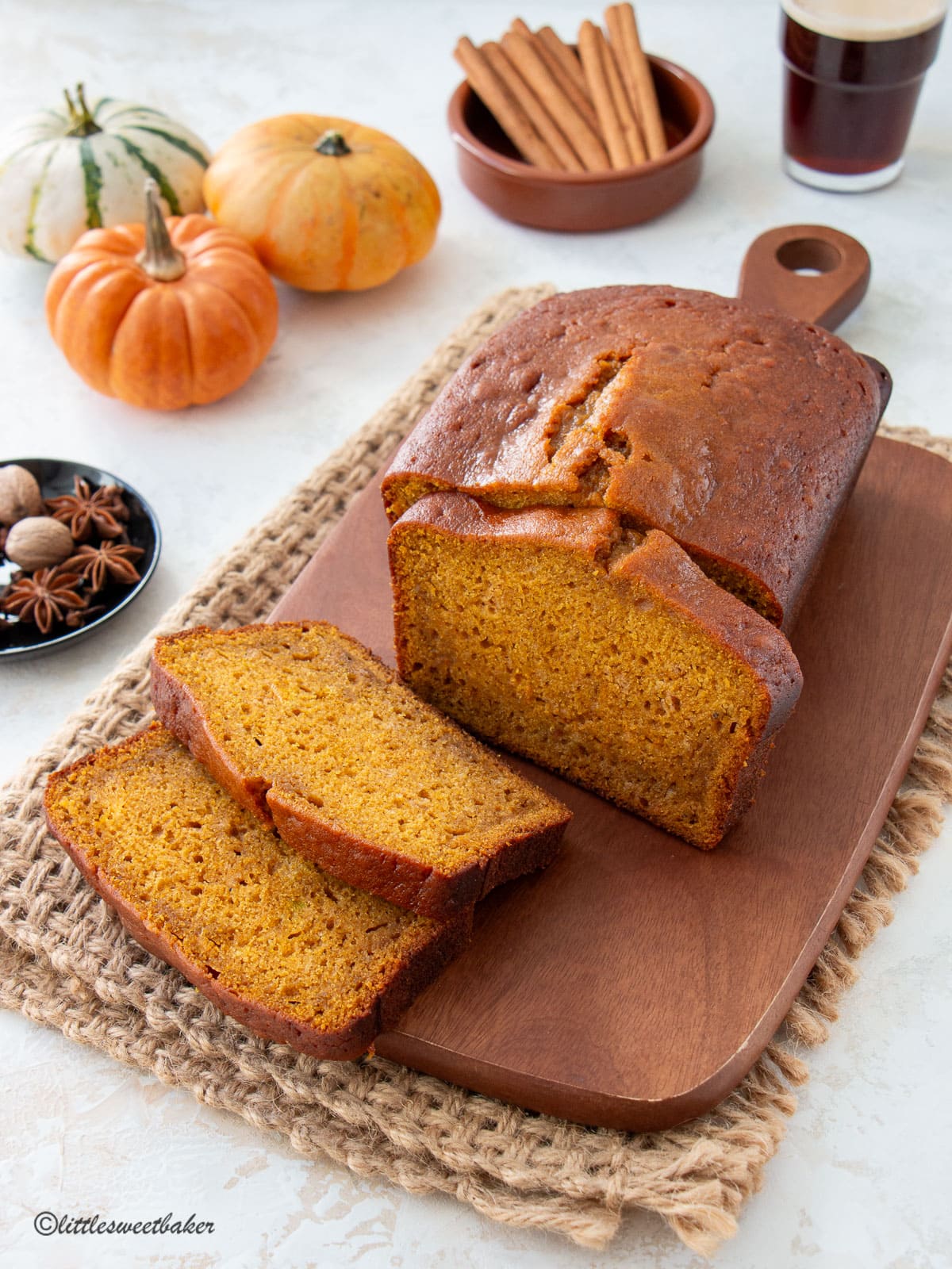 A loaf of pumpkin bread on a wooden cutting board with three slices cut.
