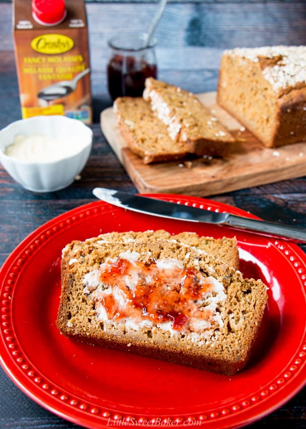 A slice of quick brown bread with butter and jam on a red plate.