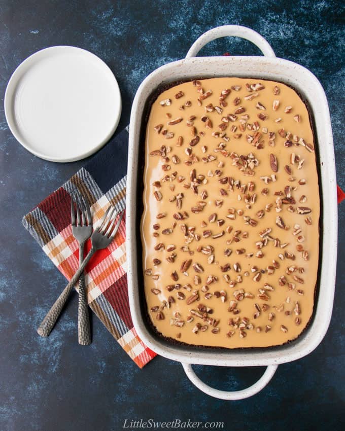 A whole gingerbread cake with glaze in a white porcelain baking pan with a dark blue background.