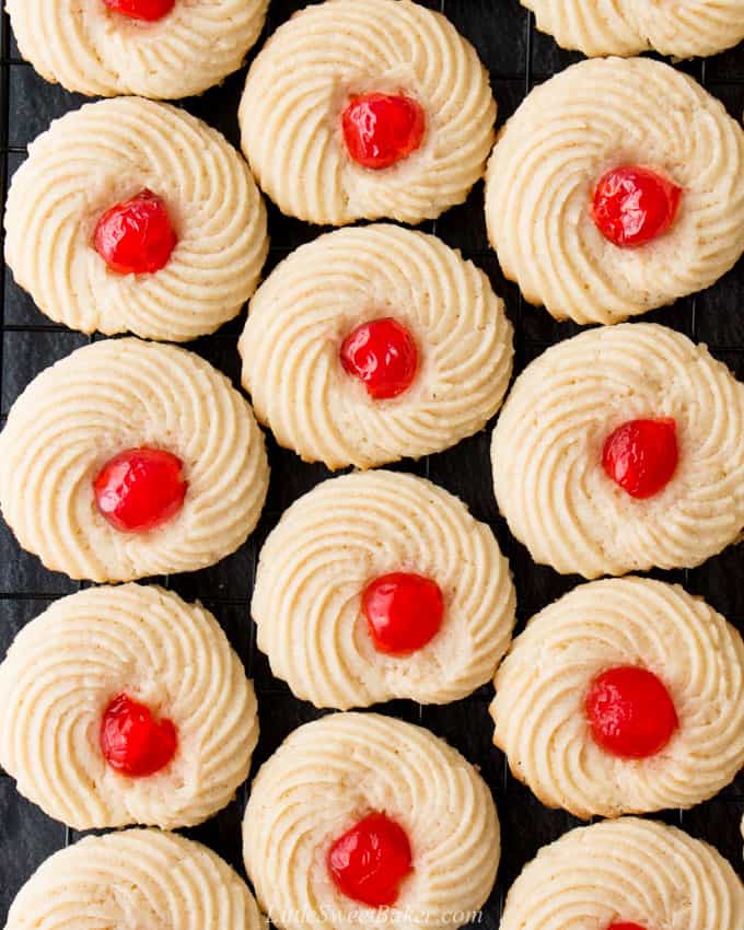Butter cookies with candied cherries on a cooling rack.