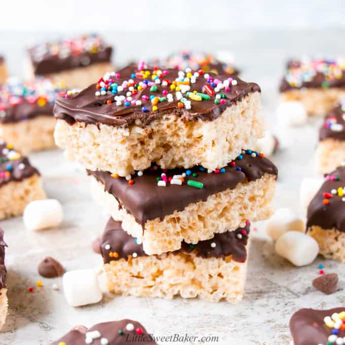 A stack of chocolate dipped rice krispie treats with a bite.