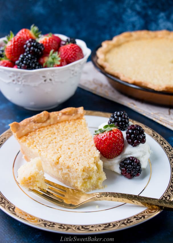 A slice of buttermilk pie on a white and gold plate with a piece on a fork.