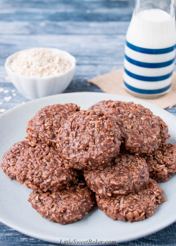 A plate of no-bake cookies with a glass of milk and rolled oats in the background.