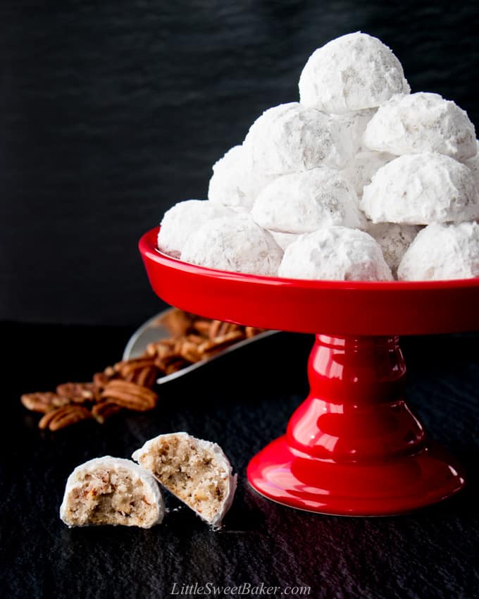 snowball cookies on a red dessert stand with pecans in the background.