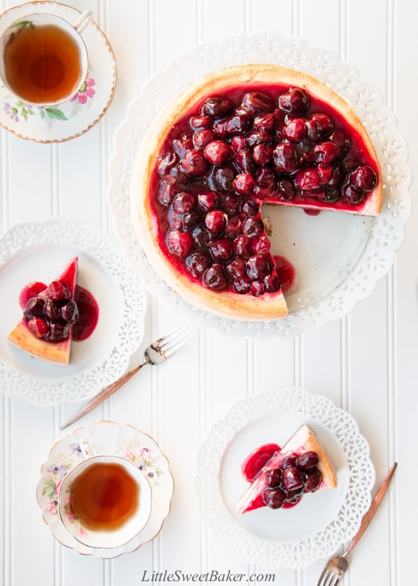 An overhead view of a cherry cheesecake and two slices on serving plates.