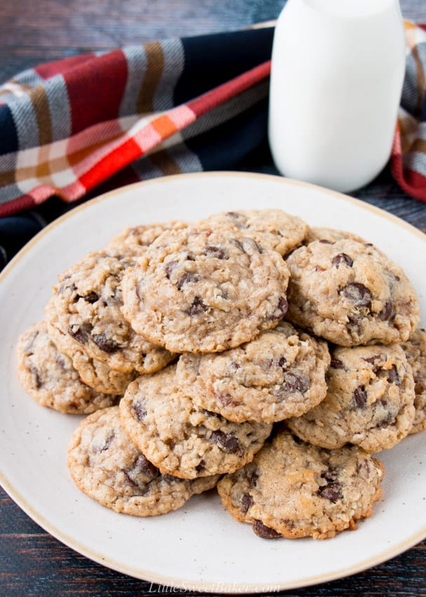 A plate of cowboy cookies with a glass of milk and plaid napkin.