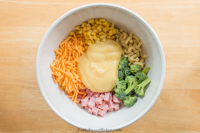 A bowl of ham, broccoli, noodles, corn, cheese and cream of chicken soup.
