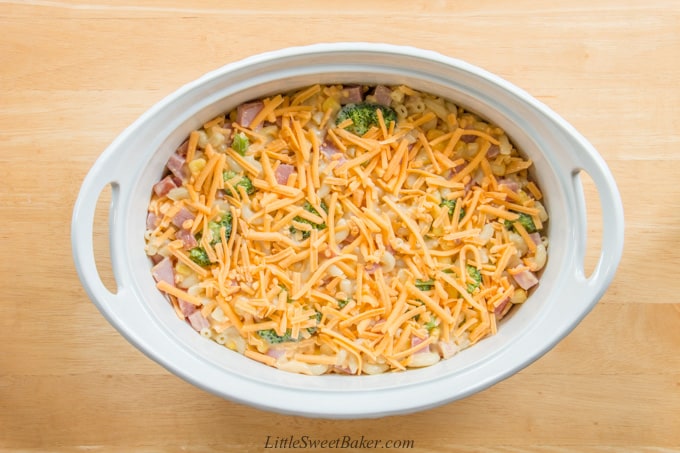 A ham and vegetable casserole topped with cheese ready to be baked.